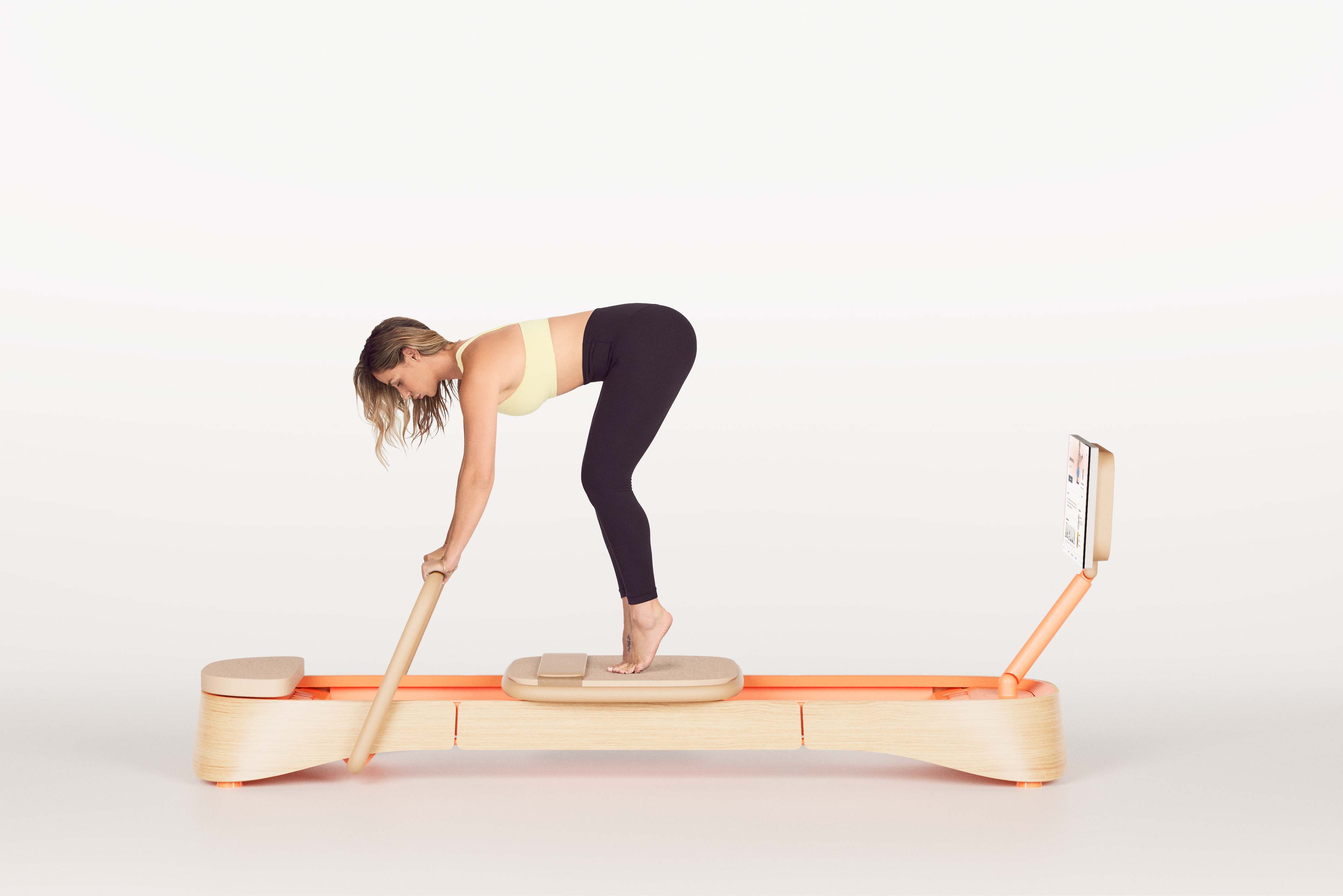 Frame fitness co-founder Melissa Bentivoglio demonstrating pilates exercises on their signature smart reformer